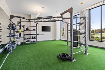 a home gym with green turf and weights equipment and a window